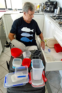 A man in a wheelchair does some rehabilitation exercises to move containers into a draw.