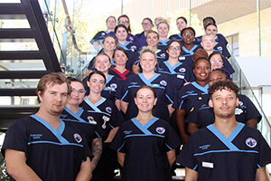 A large group of 2023 nursing and midwifery graduates standing together on an internal stairwell