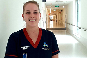 A female nurse stands in a hospital hallway