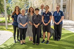 Seven people stand in a garden setting