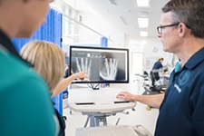 Two health professionals review a medical image on a computer monitor