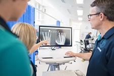 Two health professionals review a medical image on a computer monitor