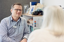 Clinical Nurse Coordinator Radiation Oncology Mirko Hessel sits at a desk in conversation with a woman