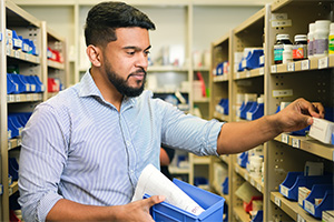A man selects medication items from a shelf