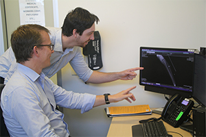 Two men review an x-ray image on the compute screen