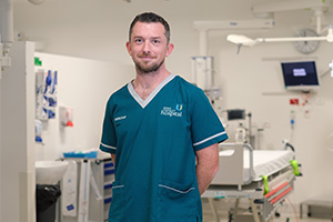 A male consultant wearing Fiona Stanley Hospital scrubs stands in a treatment area