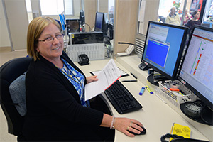 A woman sits in front of two computer screens