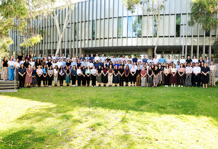 125 medical interns standing all together in a courtyard, smiling.