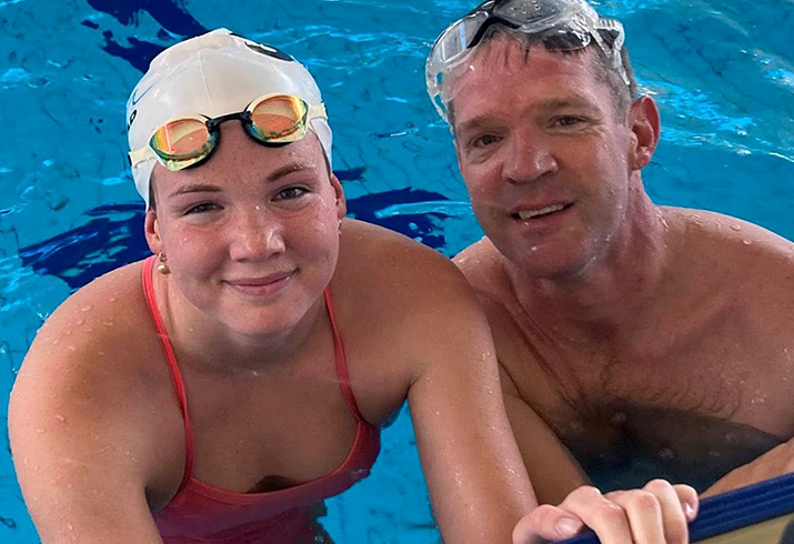 Eilidh Milne (left) wears a swimming cap and goggles in a pool beside her father Alastair Milne
