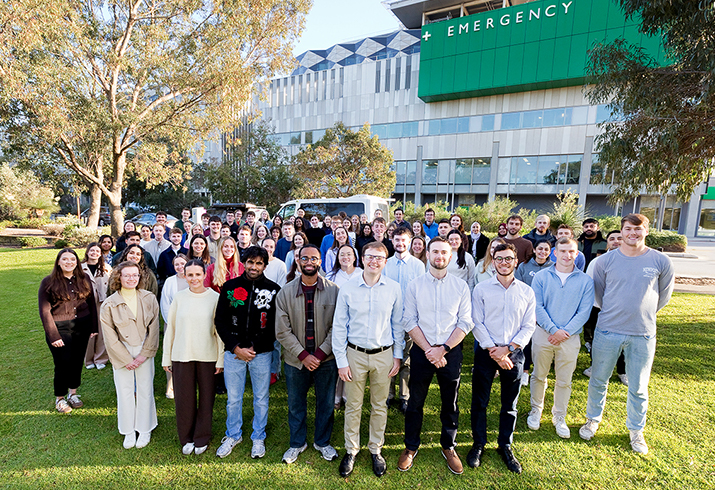 Large group of doctors standing outside in front of a hospital.